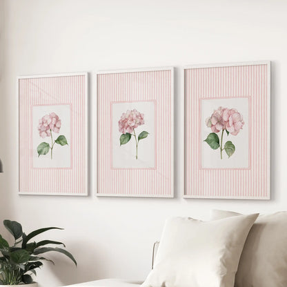 Three-piece wall hanging of vintage cottage florals in white frames behind a couch in a sitting room.