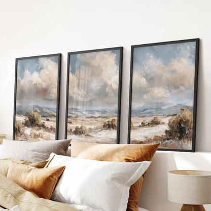 Neutral landscape prints, set of three, in black frames bring soft beige, brown, and blue wall art to a bedroom, styled as a calm row above the bed.