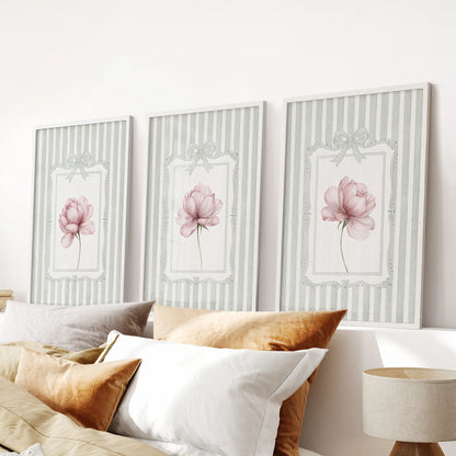 Three-piece peony botanical wall art set in white frames, displayed above a bedroom headboard.