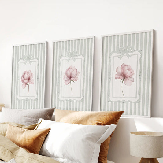 Three-piece peony botanical wall art set in white frames, displayed above a bedroom headboard.