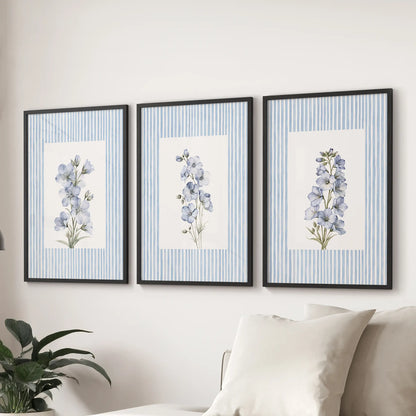 Three-print wall art set of vintage blue floral illustrations in black frames, arranged behind a couch in a lounge.