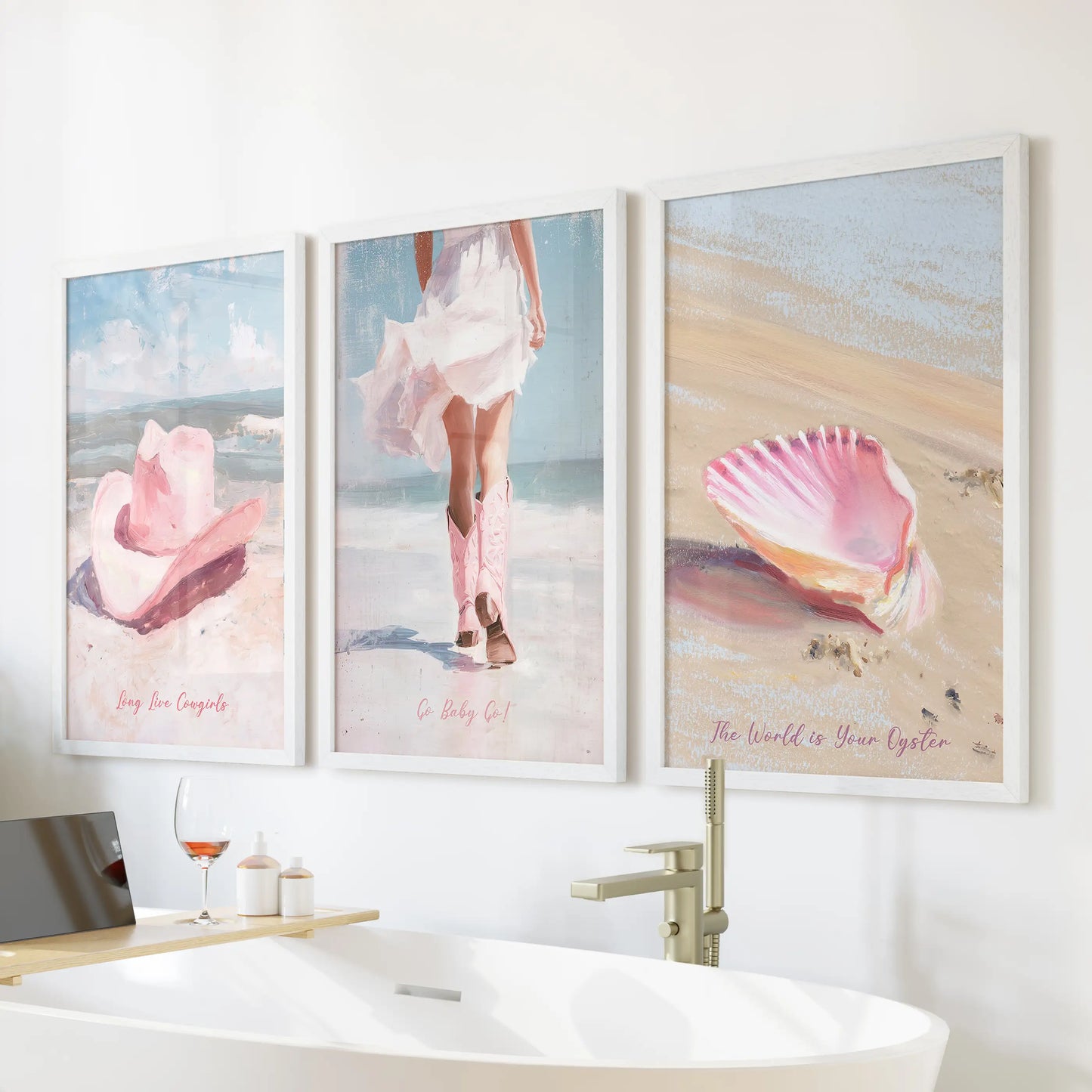 A white-framed wall print trio showing pink cowgirl hats sits over a freestanding tub, bringing soft coastal-western energy to the bathroom.
