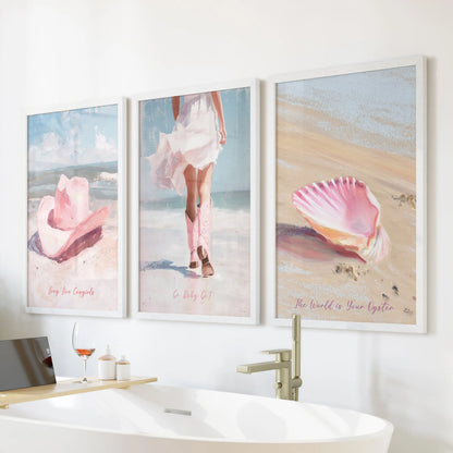 A white-framed wall print trio showing pink cowgirl hats sits over a freestanding tub, bringing soft coastal-western energy to the bathroom.