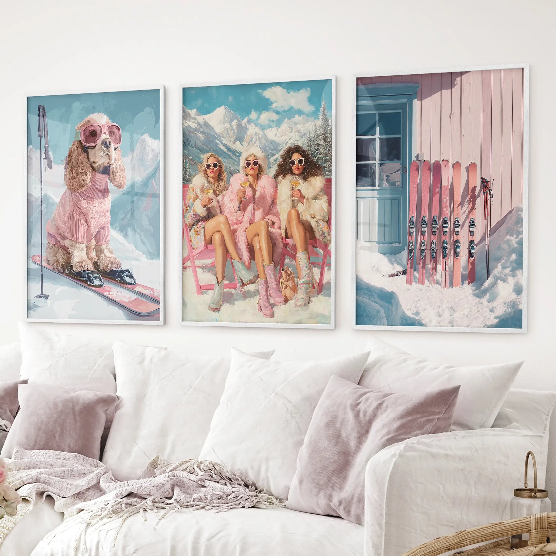 Pink ski wall decor trio – dog skier, fashionable women, and cabin with skis. White frames above the sofa.