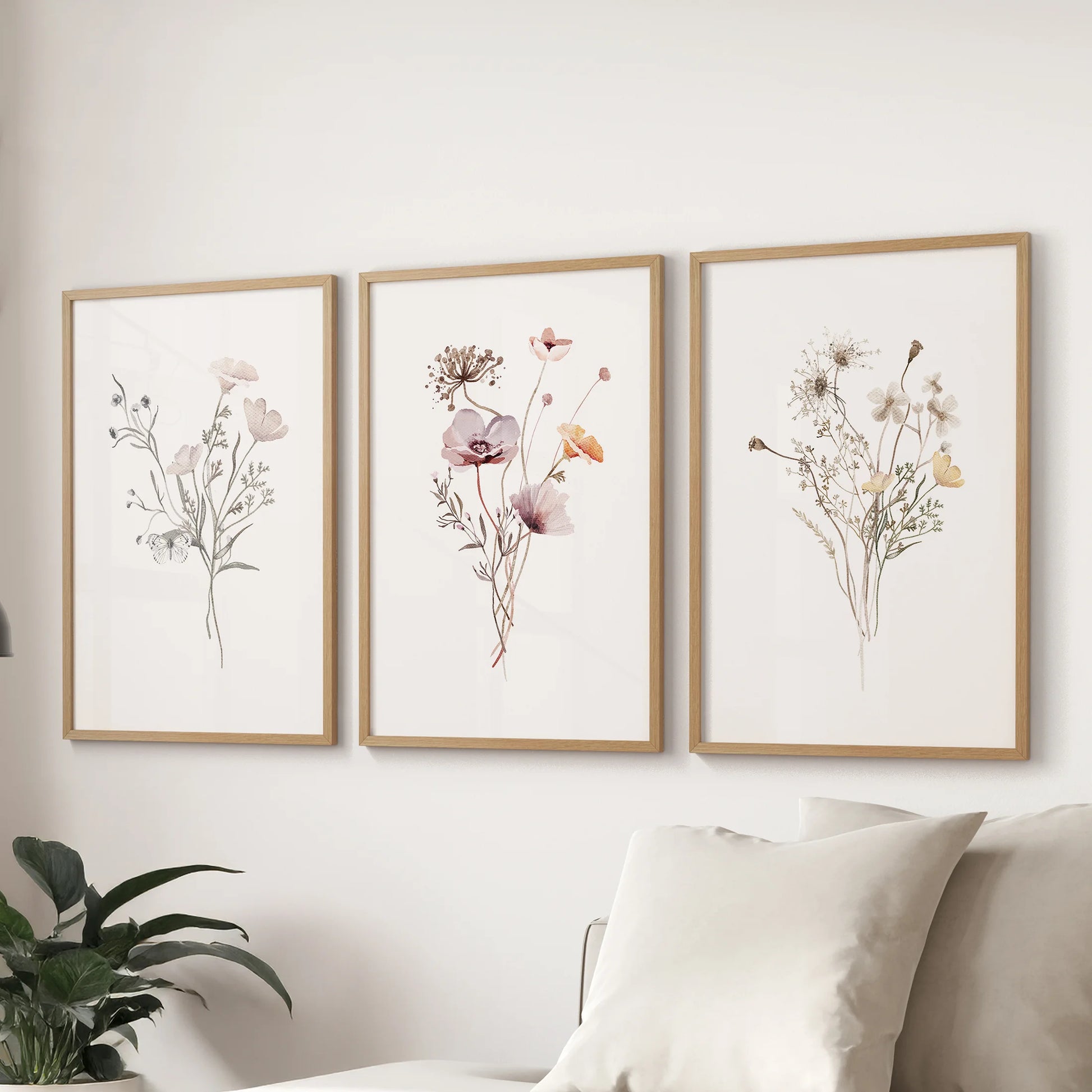 Neutral botanical florals in wooden frames, set of three art prints, span behind the sofa to lighten the living room with soft watercolor detail.