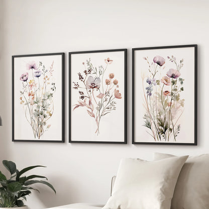 A set of three botanical floral posters in sleek black frames, arranged over the sofa to refresh the living room wall with natural color.