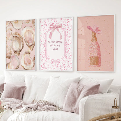 Pink glam prints  oyster artwork, champagne bottle with glitter, and cute typography. White frames over the couch.