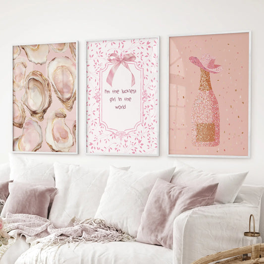 Pink glam prints  oyster artwork, champagne bottle with glitter, and cute typography. White frames over the couch.