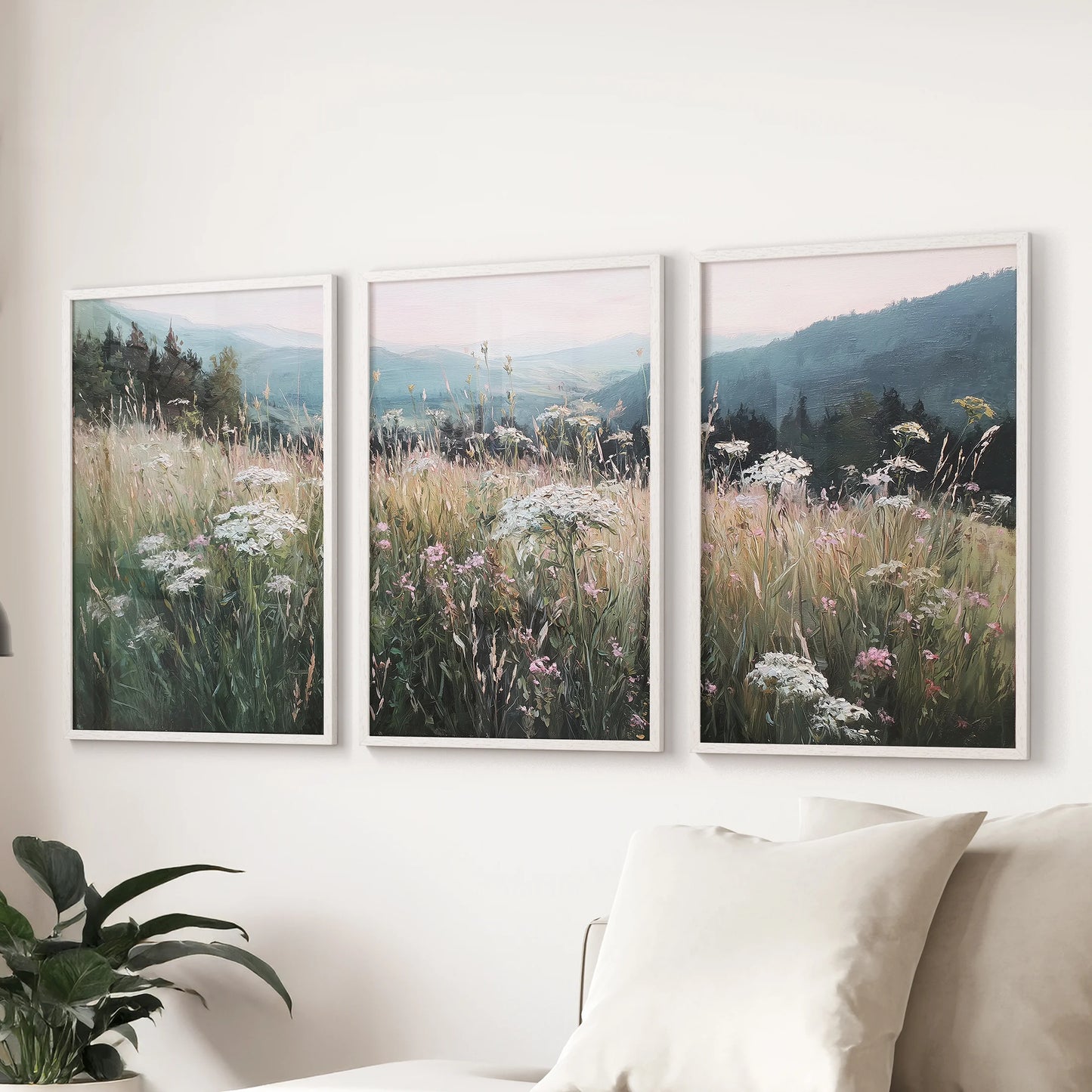 Rustic pastoral landscape 3-print gallery wall with white frames spans the lounge behind the couch, bringing airy countryside charm to the seating area.